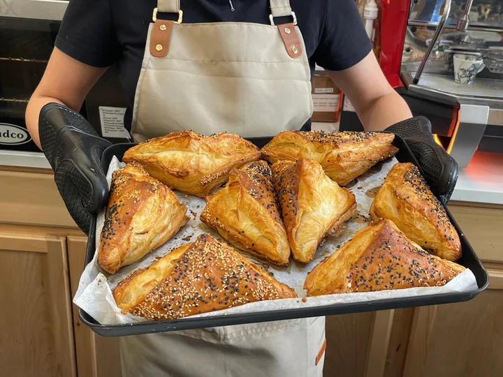 A Matto team member holding a tray of golden pastries