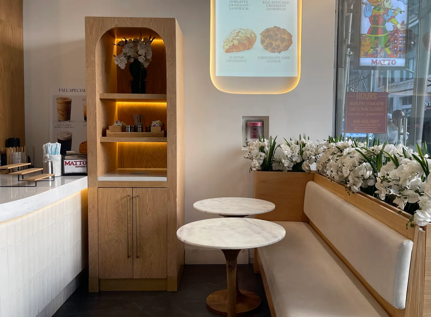 Marble tables and cushioned seating beside a flower-lined window in a Matto café